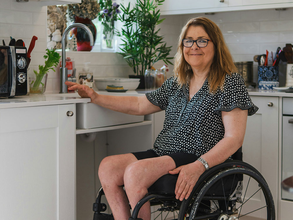 Resident in a wheelchair using an adapted accessible kitchen featuring low counter space
