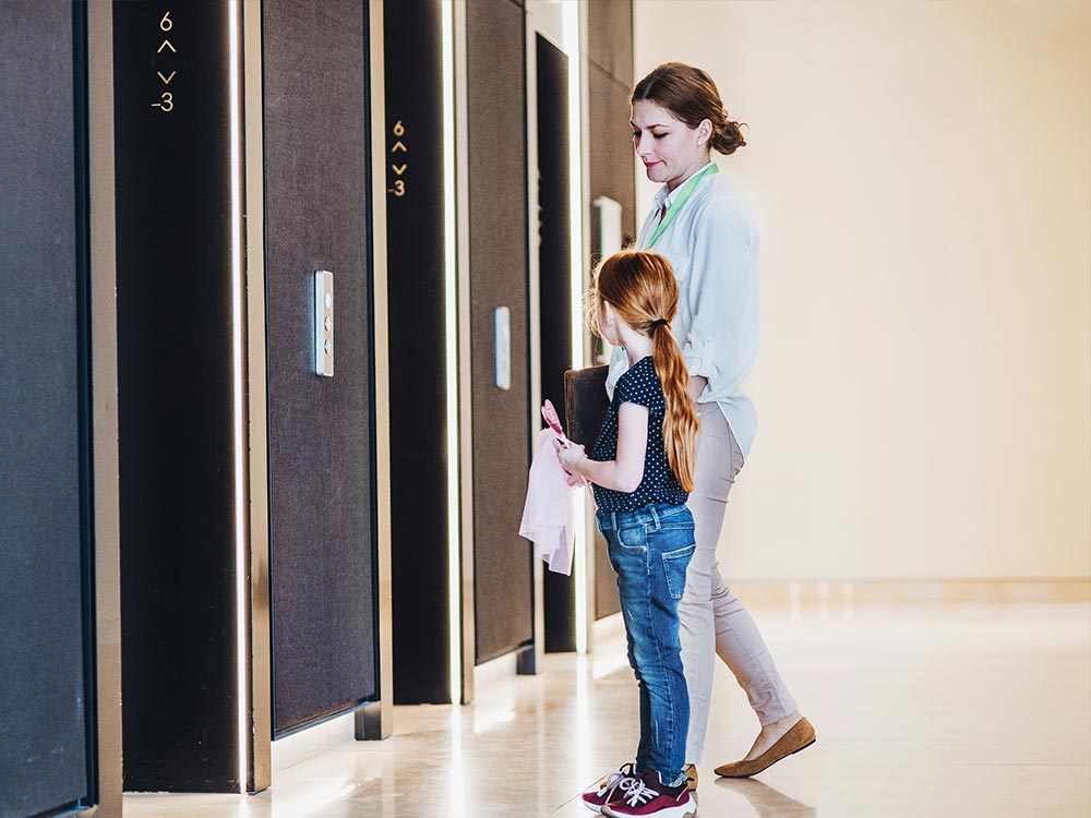 Mother and child waiting by modern elevator doors in a public sector housing development