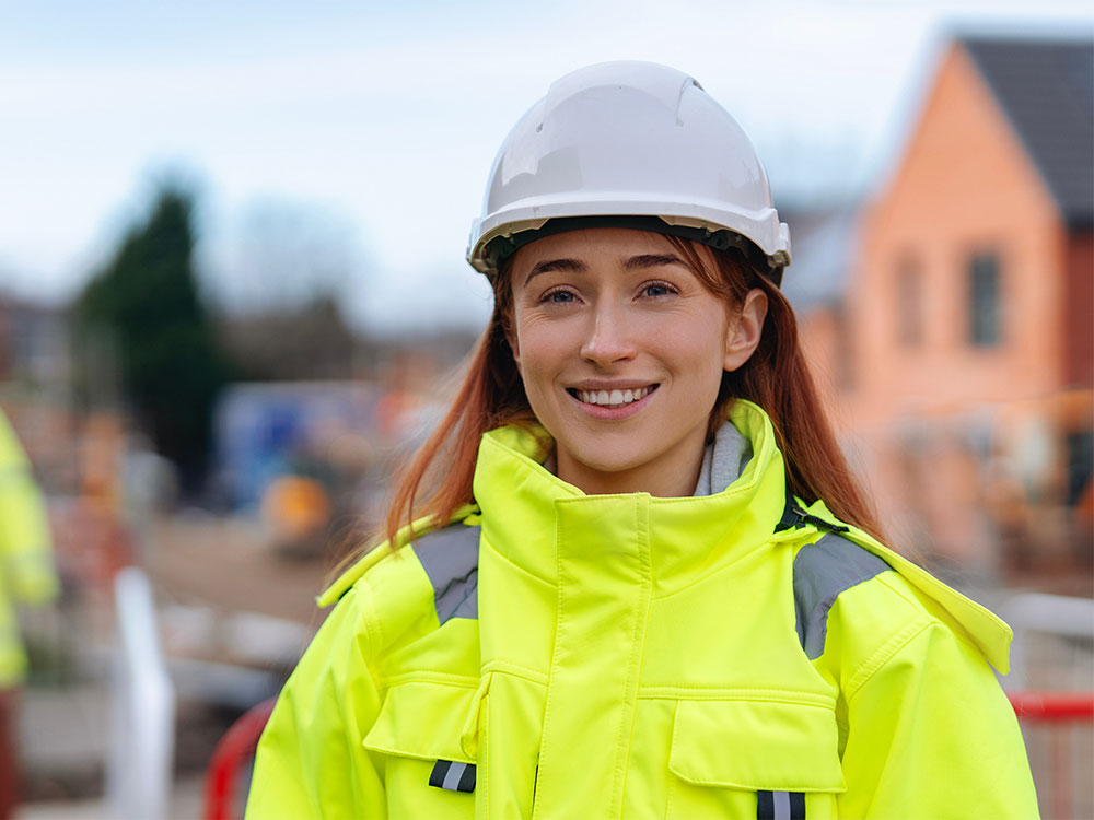 Site supervisor wearing yellow high-visibility gear on a social housing construction site