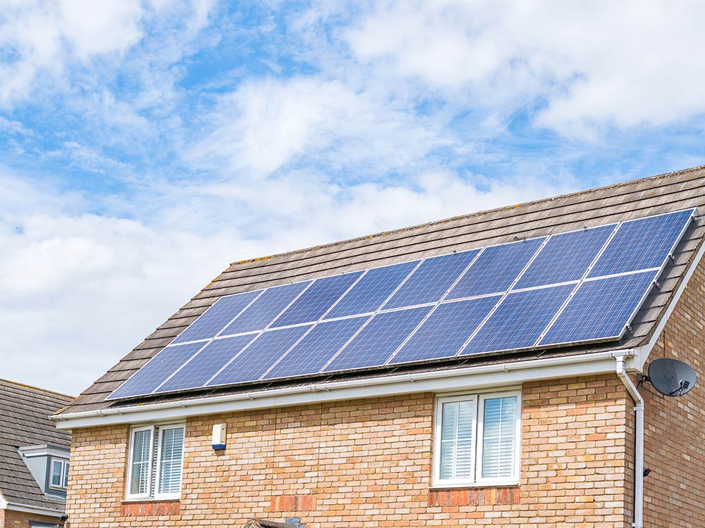 Close up of a modern red brick up home with solar panels on the roof.
